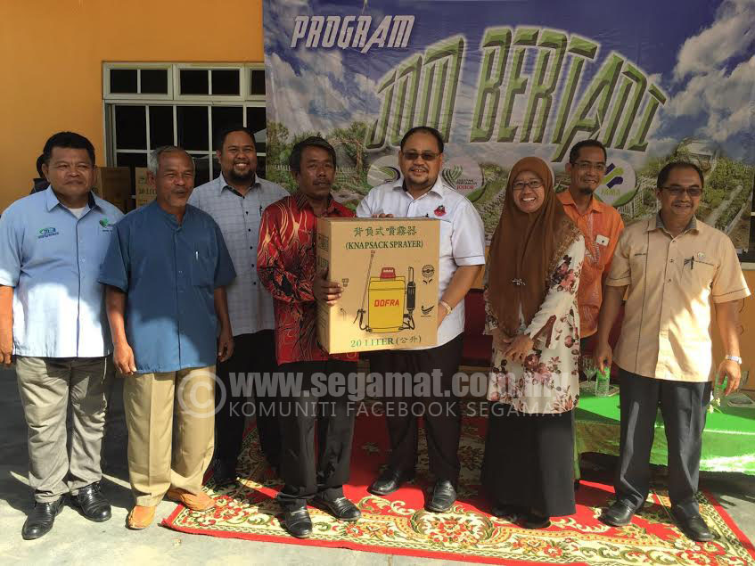 Mohd Azahar (empat,kanan) meyerahkan bantuan peralatan pertanian kepada penduduk Orang Asli Segamat Kecil.